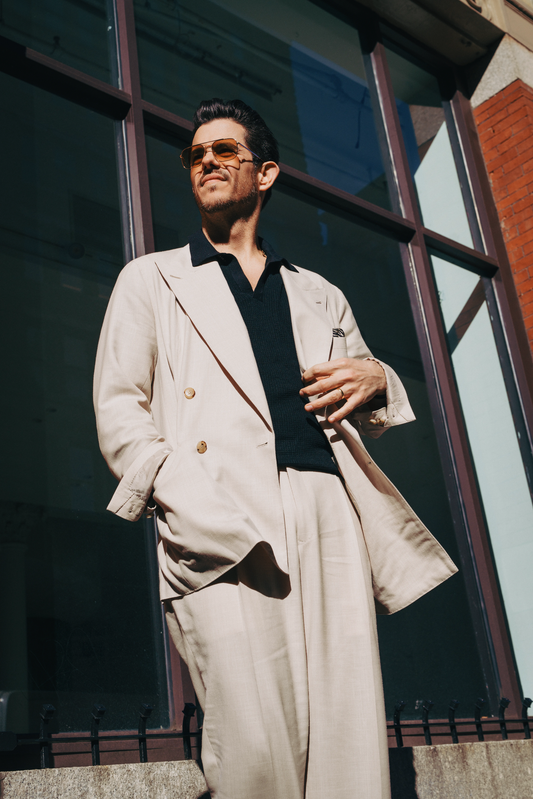 Cory in a beige double-breasted suit paired with a black open-collar knit shirt and sunglasses - custom suits nyc bespoke tailor midtown, noho